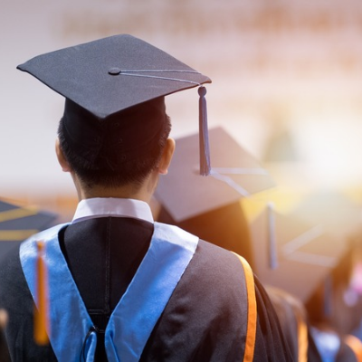 W2P 400x400 Back view of a graduate in cap and gown with a blue hood, at a graduation ceremony.